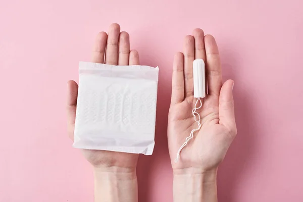 Woman hands hold sanitary pad and tampon on a pink background — Stock Photo, Image