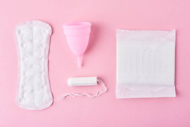 Hijyen Pad, menstrüel fincan ve tampon pembe arka planda, üst görünüm