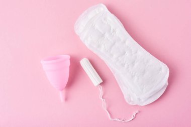 Hijyenik ped, adet kupa ve tampon pembe bir arka plan üzerinde