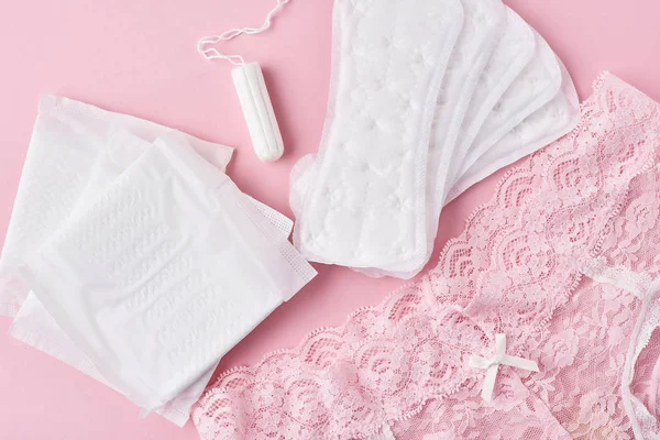 Bantalan sanitasi, cangkir menstruasi, tampon dan celana dalam dengan latar belakang merah muda — Stok Foto