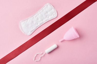 Hijyenik ped, adet kupa ve tampon pembe bir arka plan üzerinde