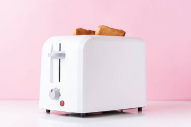 Pembe arka plan üzerinde kavrulmuş tost ekmek ile beyaz tost makinesi, yakın