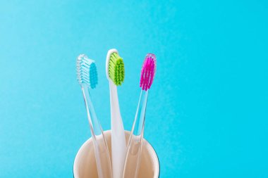 Mavi bir backgroun cam üç plastik renkli diş fırçaları