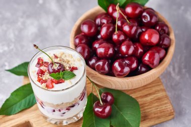 Cam kavanozda yaz kiraz ve gri bir arka plan üzerinde ahşap kase taze çilek ile Smoothie