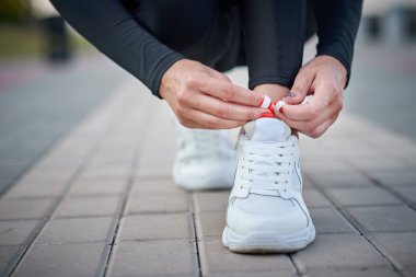Kadın koşmak için hazırlansın. Spor ayakkabılara ayakkabı bağcıkları bağlayan kadın elleri
