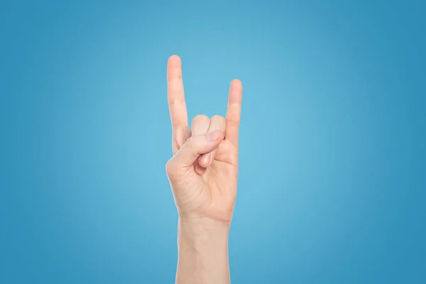 Mão mostrar gesto de rocha em um fundo azul, close-up . — Fotografia de Stock