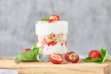 Cam kavanozda yaz çilek ve gri bir arka plan üzerinde ahşap kase taze çilek ile Smoothie