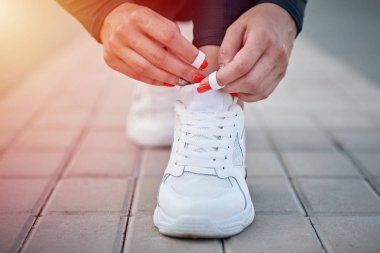 Kadın koşmak için hazırlansın. Spor ayakkabılara ayakkabı bağcıkları bağlayan kadın elleri