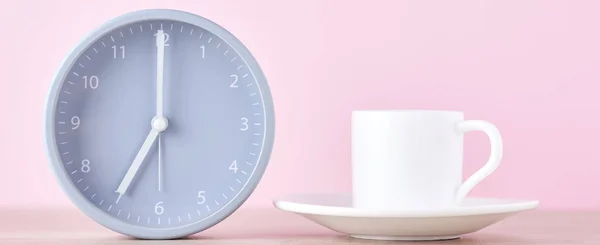 Classic gray alarm clock and white coffee cup on a pink background, long banner
