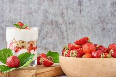 Çilek granola veya meyve lifi cam ve taze çilek bir kesme tahtası üzerinde, yakın. Sağlıklı kahvaltı