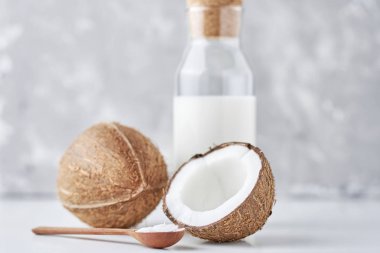 Cam şişede hindistan cevizi sütü ve gri arka planda taze hindistan cevizi.