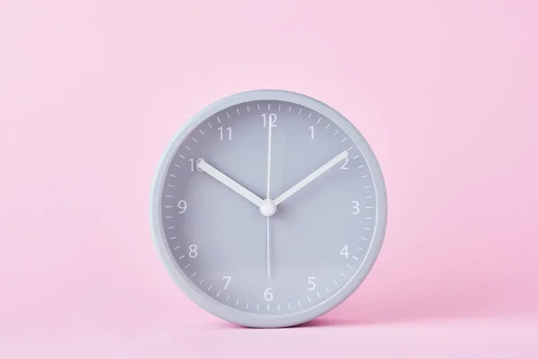 Relógio de alarme clássico cinza em um fundo rosa pastel, close-up — Fotografia de Stock