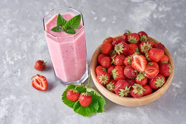 Batido de fresa en frasco de vidrio y fresas frescas en cuenco de madera sobre un fondo gris. Desayuno saludable —  Fotos de Stock