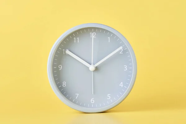 Relógio de alarme clássico cinza em um fundo amarelo pastel, close-up — Fotografia de Stock
