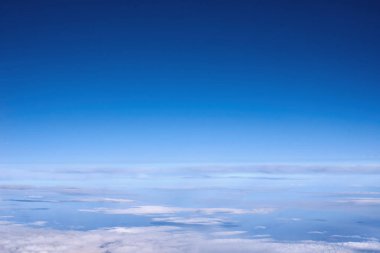 Uçak penceresinden bulutların üzerinde mavi gökyüzü