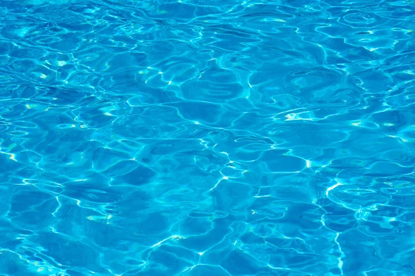 Fond d'eau dans une piscine bleue, surface de l'eau avec reflet du soleil — Photo