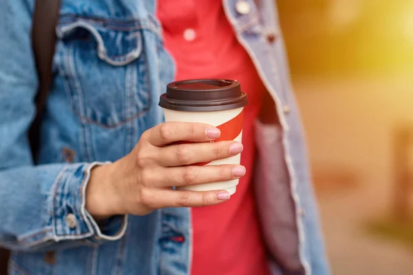 Main de femme avec tasse de café en papier à emporter dans une rue de la ville — Photo