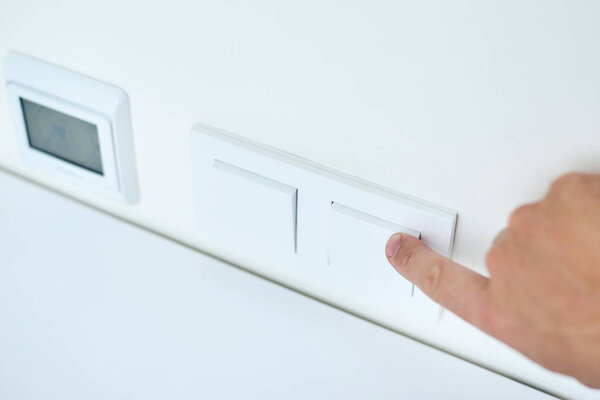 Hand is turning on or off on light switch, closeup