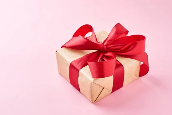 Confezione regalo chiudibile in carta artigianale con nastro rosso su fondo rosa — Foto Stock