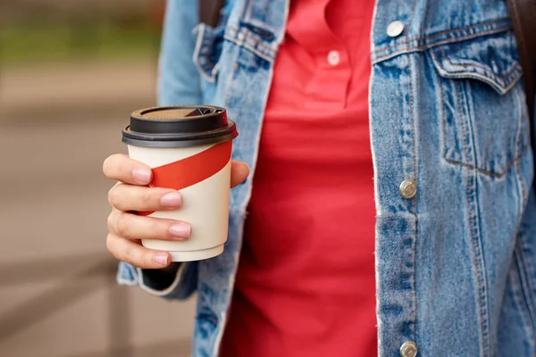 Main de femme avec tasse de café en papier à emporter dans une rue de la ville — Photo