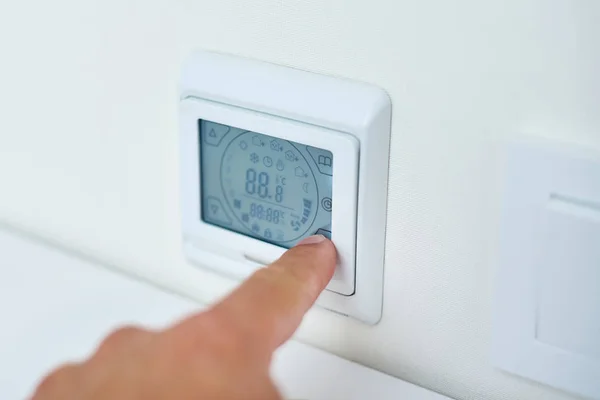 Uomini temperatura di regolazione della mano sul pannello di controllo riscaldamento a pavimento — Foto Stock