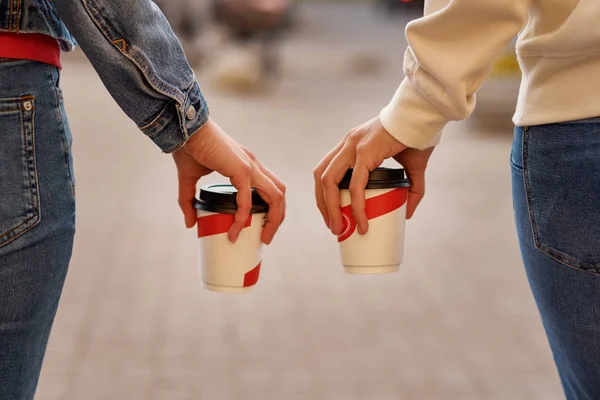 Woman hand with paper cup of coffee take away in a city street