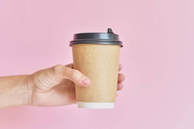 Pembe backgroun üzerinde kahve kağıdı fincan tutan kadın el Mockup