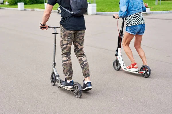 Мужчина и женщина ездят на электрических скутерах по городу — стоковое фото