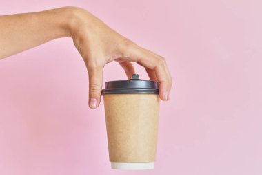 Pembe backgroun üzerinde kahve kağıdı fincan tutan kadın el Mockup