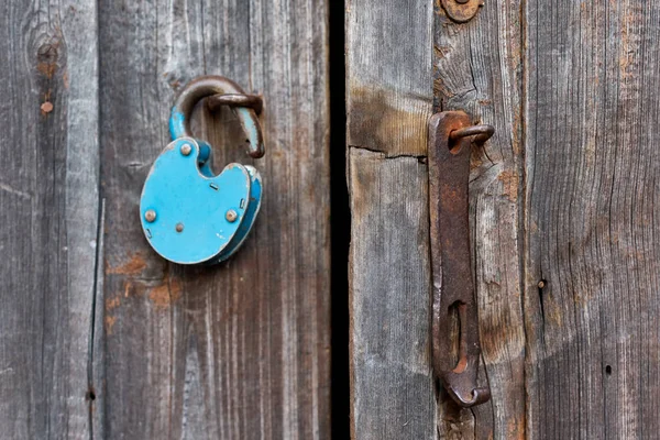 Blue old rusty unlocked padlock on wooden door