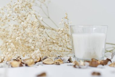 Beyaz bir masanın üzerinde çiçek dekoru olan mum. Samimi ve higge backgr