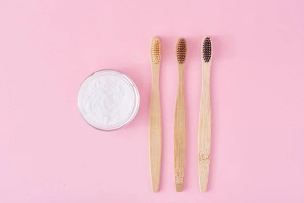 Three wooden bamboo toothbrushes and baking soda powder in glass — Stock Photo, Image