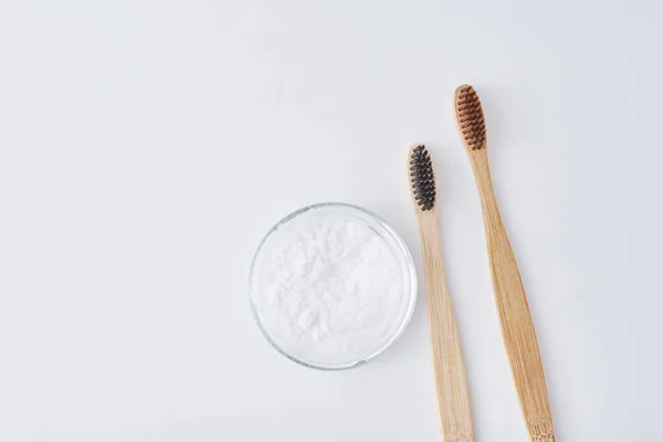Two wooden bamboo toothbrushes and baking soda powder in glass j — Stock Photo, Image