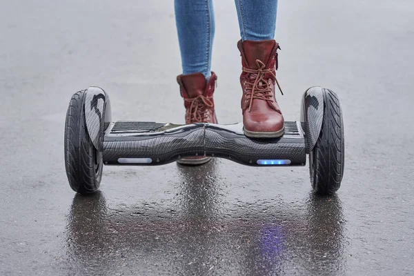 Primer plano de la mujer que utiliza hoverboard en el camino de asfalto. Pies en elec —  Fotos de Stock