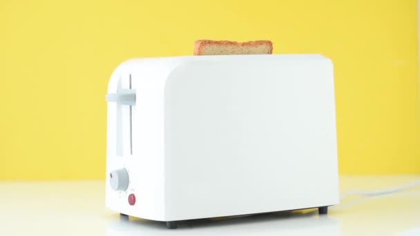 手把烤面包机面包放在黄色背景的白色烤面包机上 然后打开烤面包机 用厨房用具准备早餐 — 图库视频影像