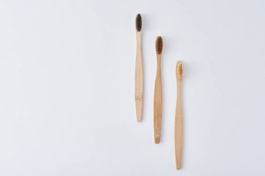 Beyaz arka planda üç ahşap bambu diş fırçası.