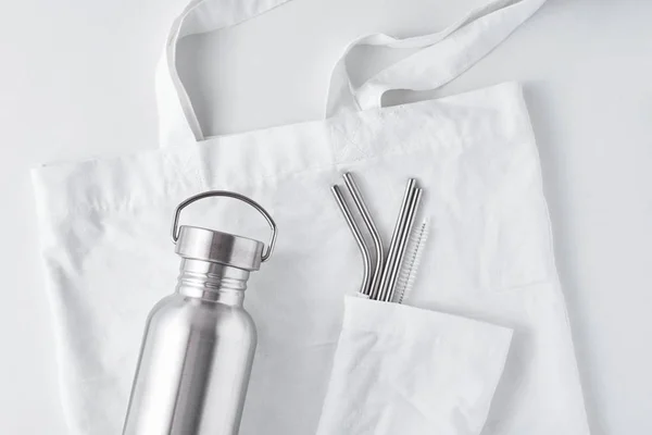 Алюминиевая бутылка и металлические трубки в хлопчатобумажном мешке на сумке . — стоковое фото