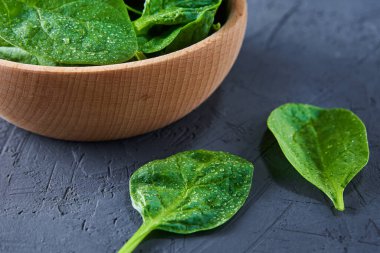 Koyu arkaplandaki ahşap kasede taze ıspanak yaprakları. Organik yiyecekler