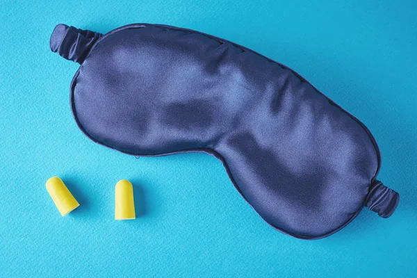 Insomnia and sleeping problem concept.Sleeping mask and ear plugs on blue background, top view