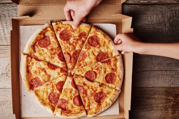 两只手从纸板箱上取下几片披萨 俯瞰全景 — 图库照片