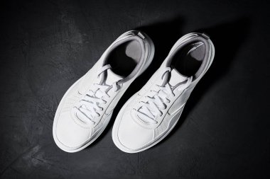 Siyah arka planda bir çift beyaz spor ayakkabı, üst görünüm