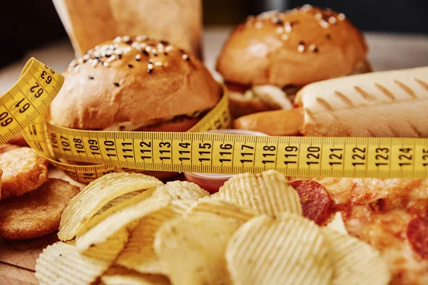 Niezdrowe Niezdrowe Jedzenie Różne Rodzaje Fast Food Przekąsek Stole Taśmą — Zdjęcie stockowe