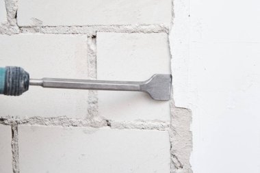 Yenileme konsepti. Yıkıcı çekiçli adam duvardaki alçıyı kaldırdı.