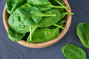 Koyu arkaplandaki ahşap kasede taze ıspanak yaprakları. Organik yiyecekler