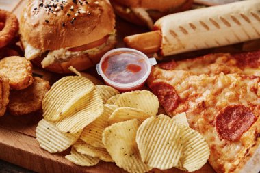 Sağlıksız ve abur cubur. Masada farklı türde fast food ve atıştırmalıklar var. Kapatın. Paket yemek.