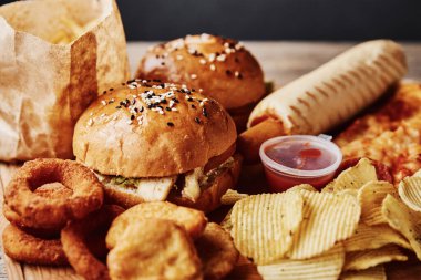 Sağlıksız ve abur cubur. Masada farklı türde fast food ve atıştırmalıklar var. Kapatın. Paket yemek.