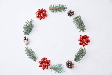 Noel kompozisyonu. Köknar ağacı dallarından yapılmış çelenk ve beyaz arka planda neşeli çam kozalakları, üst manzara