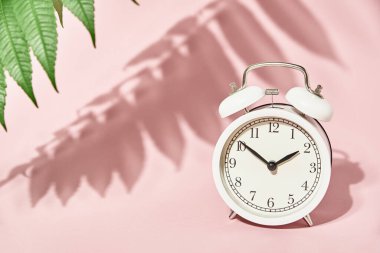 Beyaz alarm saati ve pastel pembe arka planda gölgeler bırakıyor. Yaratıcı asgari zaman kavramı