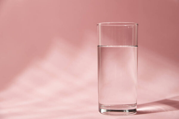 Glass of water on pink background