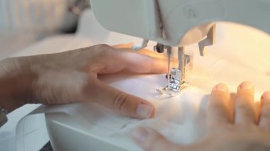 Dikiş makinesi iğnesinin yakın görüntüsü ve iplikli baskılı ayak. Evde kumaş dikmek için elektrikli dikiş makinesi kullanan bir kadın. Dikiş dikme, terzilik ve el işi kavramı